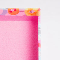 A corner detail of a NiMi Projects UK peony patterned Yuzen Washi Pen box, made in Japan by traditional chiyogami washi paper craftspeople, featuring a pink interior wrapped with the patterned washi paper of yellow and orange peonies.