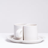 Ceramic Japan Pair Cups — two white porcelain semicircle half cups — sit facing each other on a specially designed shared saucer, on display at NiMi Projects UK
