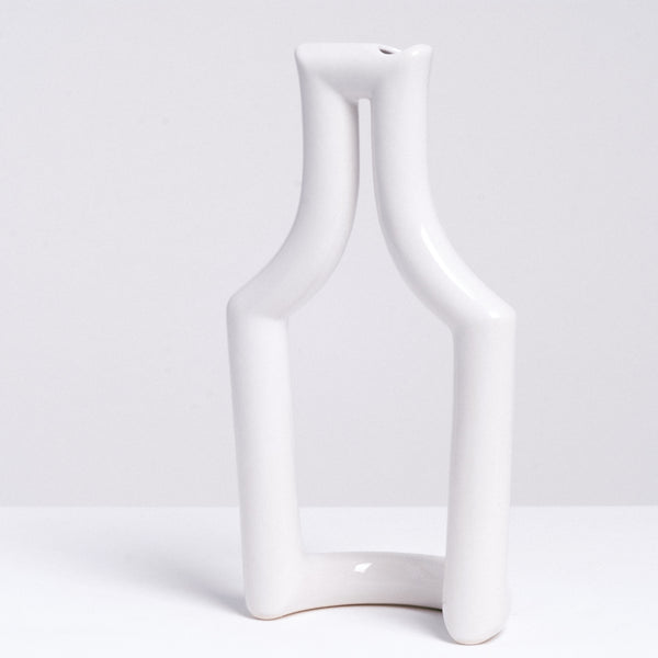 A white Still Green  porcelain tubular vase in the shape of a bottle, made by Ceramic Japan and sold at NiMi Projects UK.