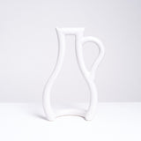 A white Ceramic Japan Still Green Water Jug tubular vase, shaped in the silhouette of a jug with a handle, on display at NiMi Projects UK. 