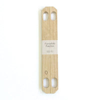 A pair of Patchin oak wood accessories to convert a furoshiki wrapping cloth into a bag, available at NiMi Projects.