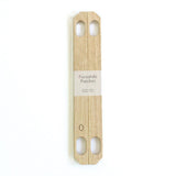 A pair of Patchin oak wood accessories to convert a furoshiki wrapping cloth into a bag, available at NiMi Projects.