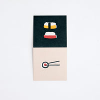 A Japanese Motif Mini Card, laid flat to show both sides, with one side showing  picture of two pieces of nigiri sushi on a black background, and a pair of chopsticks holding a norimaki sushi roll on a cream background on the other side. Printed in Japan and available at NiMi Projects.