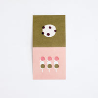 A Japanese Motif Mini Card, laid flat to show both sides, with one side showing an illustration of three sticks of hanami dango (pink, white and green mochi balls) on a pink background, and the other side featuring a white shiro daifuku (mochi ball) dotted with black beans. Printed in Japan and available at NiMi Projects.