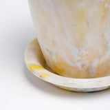 A close up image of a white Buoy recycled marine plastic plant pot and saucer, showing the marbled effect of the pieces of plastic melded together, shown at NiMi Projects