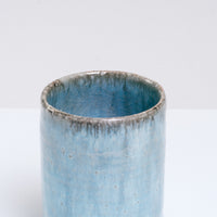A close up view of the top of an Asemi Iga-yaki Hydrangea Japanese tea cup available at NiMi Projects UK. The rim of the cup reveals a dark grey clay showing through  the  cup's pale blue glaze. 