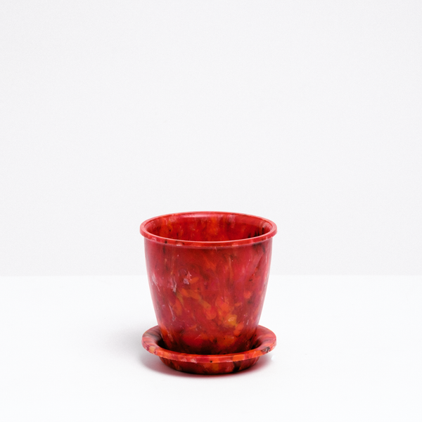 An environmentally conscious red Buoy Deco rotund plant pot, with a matching saucer, made of recycled marine plastic collected from beaches in Fukui Prefecture in Japan and on show at NiMi Projects, UK.