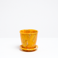 A yellow Deco recycled plastic rotund plant pot and saucer, made in Japan from recycled ocean waste plastic collected from beaches in Kanagawa Prefecture by the environmentally conscious company Buoy and on show at NiMi Projects UK.