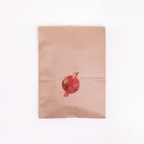 A brown paper bag featuring a cutout window in the shape of a circle with a line through it to showcase an eco-friendly red recycled ocean plastic waste Buoy leaf tray behind. Designed and made in Japan by Buoy and on show at NiMi Projects UK.