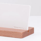 Detail of a Ceramic Japan white stone aroma card diffuser, showing the Ceramic Japan logo debossed in to the porcelain card, propped on a wooden stand.  Made in Japan and on display at NiMi Projects.,