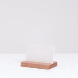 A white minimalist Ceramic Japan credit card shaped stone aroma diffuser, held upright in a natural wooden stand, made in Japan and sold at NiMi Projects UK.