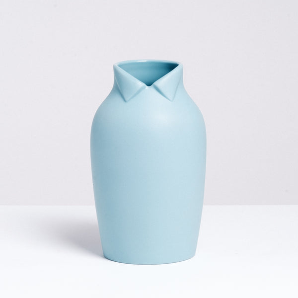 A large blue-gray Ceramic Japan x Nendo Dress Up porcelain vase, shaped like a rotund figure with a wing-tip collar at its neckline on display at NiMi Projects UK.