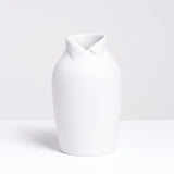 A large white Ceramic Japan x Nendo Dress Up porcelain vase, shaped like an ordinary vase but with a wing-tip collar at the neck, making it look like a figure. Made in Japan and on display at NiMi Projects UK.