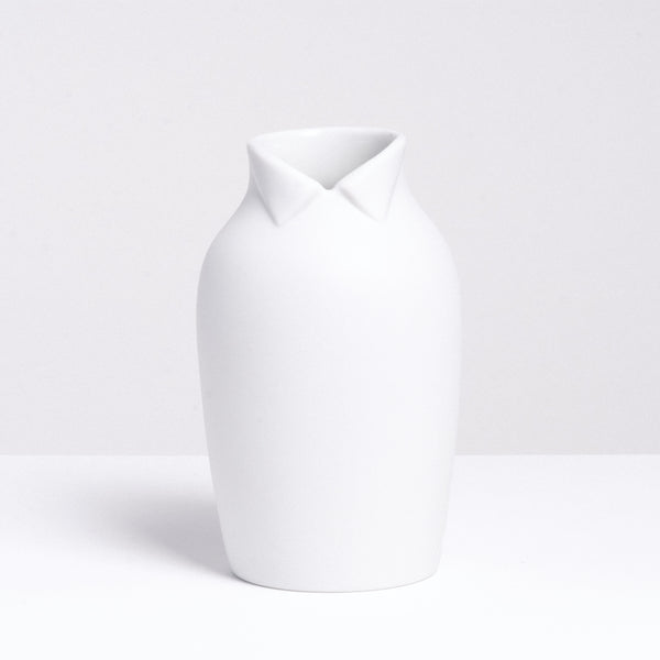 A large white Ceramic Japan x Nendo Dress Up porcelain vase, shaped like an ordinary vase but with a wing-tip collar at the neck, making it look like a figure. Made in Japan and on display at NiMi Projects UK.