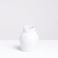 A white porcelain Ceramic Japan x Nendo Dress Up vase, with a Peter Pan collar at its neck to appear like a rotund figure. Made in Japan and found at NiMi Projects UK.