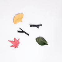 Five porcelain chopstick rests designed by Kaichiro Yamada for Ceramic Japan. Three are shaped like leaves — a pink maple leaf, green cherry-tree leaf and a yellow ginkgo leaf — and two shaped like little twigs. Made in Japan and available at NiMi Projects UK.