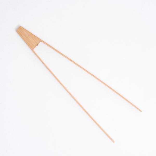 A pair of 30 cm Japanese bamboo kitchen tongs with a triangular top piece and grooved ends, ideal for serving salad, barbecues and flipping foods in the kitchen. Available at NiMi Projects UK.