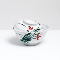 A vintage Japanese ceramic donburi (rice dish) lidded bowl in white, with a hand-painted wild orchid design of green leaves and red flowers on its side and lid. On display at NiMi Projects UK.