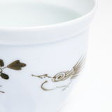 A close-up image of the top of a vintage Arita-yaki Japanese porcelain cup at NiMi Projects UK. The detail featured shows the pale blue glaze and a hand-painted pheasant in gold on the side of the cup.