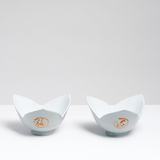 Two NiMi Projects' tulip-shaped vintage Arita-yaki Japanese porcelain bowls, each with three petal-shaped sides glazed in a pale celadon green, and featuring kanji writing expressing notions of good fortune.