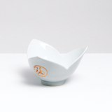 A tulip or lily shaped vintage Arita-yaki Japanese porcelain bowl, with three petal-shaped sides glazed in a pale celadon-green and featuring kanji symbolizing good fortune. On show at NiMi Projects UK.