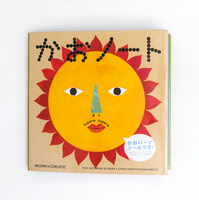 The front cover of NiMi Projects UK's  Kokuyo Face Sticker Book, featuring a picture of a yellow sun with orange flames, a pair of eyes, a nose and a mouth, illustrated by Japanese artist unit Tupera Tupera. 