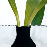 A closeup of the top of a NiMi Projects' navy blue and white Moheim Silhouette knitted vase cover.