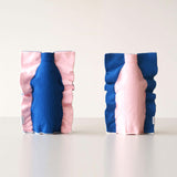 Two Moheim Silhouette vases, displayed side by side to show both sides of the product. The knitted vase features a silhouette of a bottle in blue on a pink background on one side, and a pink silhouette on a blue background on the other.