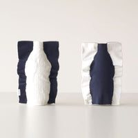 Two Moheim Silhouette vases, displayed side by side to show both sides of the product. The knitted vase features a silhouette of a bottle in white on a navy blue background on one side, and a navy blue silhouette on a white background on the other.