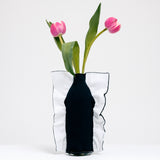 A side view of a Moheim Silhouette jersey knit vase cover available at NiMi Projects UK, featuring a navy blue silhouette of a vase on a navy white background and stretched over a bottle holding two pink tulips.