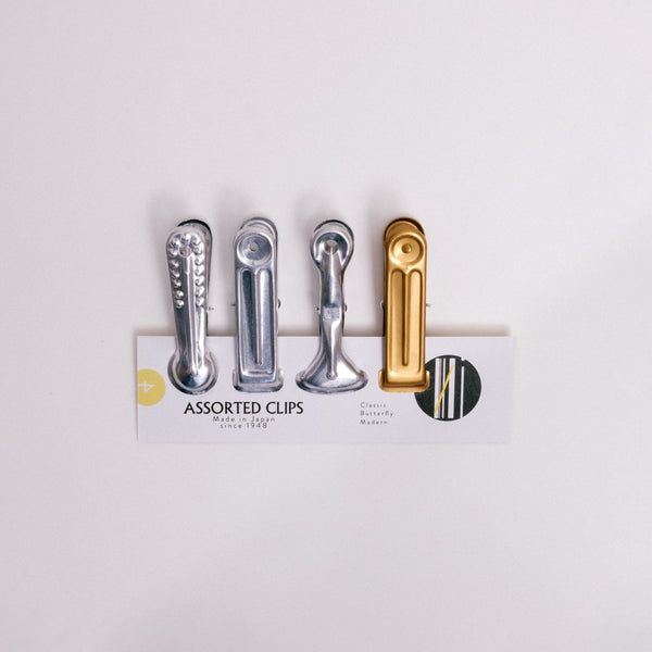 A set of four different Japanese Nanmoku aluminum clips  — modern, plain silver, butterfly, plain gold - displayed on  a NiMi Projects UK card.