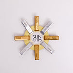 A NiMi Projects UK set of 8 aluminium SUN logo clips (4 gold and  4  silver), made in Japan by  Nanmoku, on display clipped around a circular card.