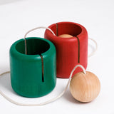 Two NiMi Projects Ototama Cup and Ball toys in green and red. Each Ototama has a cup with a ball attached to its center, and is played like the Japanese game of kendama.