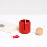 A NiMi Projects wooden kendama-like Ototama Cup and Ball toy, with a red cup and a natural colored ball attached by a white cord.