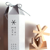 Japanese designer Sukima's Hositoshi wooden asterisk/star-shaped building blocks, beside their hexagonal, grey paper card storage box with a drawstring tie at the top. Available at NiMi Projects UK