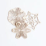 Three Sukima Japanese Shina wood snowflake Christmas ornaments, laid flat slightly overlapping each other, available at NiMi Projects UK 