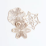Three Sukima Japanese Shina wood snowflake Christmas ornaments, laid flat slightly overlapping each other, available at NiMi Projects UK 
