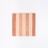 A Tosa Ryu expandable trivet of Hinoki (Japanese Cypress) and Cherry wood slats, here closed into its compact striped square form at NiMi Projects UK.