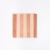 A Tosa Ryu expandable trivet of Hinoki (Japanese Cypress) and Cherry wood slats, here closed into its compact striped square form at NiMi Projects UK.