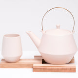 A pink Frustum Japanese teapot and cup, designed by Knot, displayed on a Tosa Ryu expandable trivet of a hinoki and cherry wood slats. All made in Japan and on show at NiMi Projects UK.