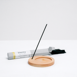 Trunk Design's Gardenia Daily Japanese incense sticks, in an open box lies behind a Trunk Design circular wooden incense stick holder at NiMi Projects UK.