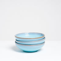 A side view of three stacked small blue vintage Japanese ceramic round bowls.