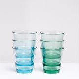 Two stacks of three Spash colored glass tumblers, made in Japan by Toyo Sasaki Glass. One stack of green tumblers, and one stack of blue, on show at NiMi Projects UK.